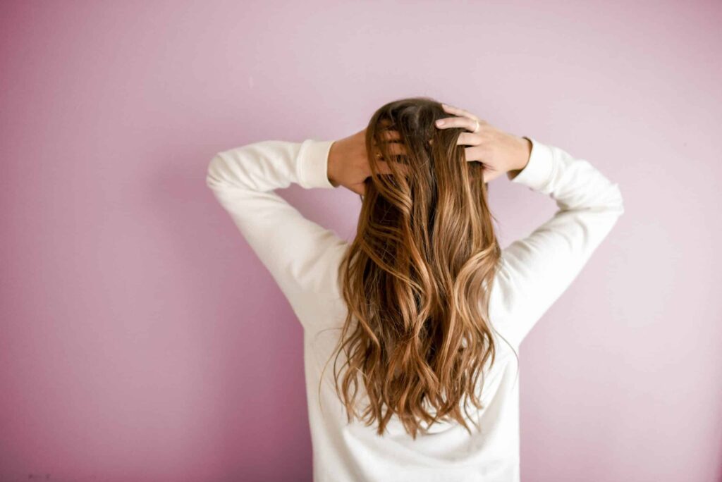back of woman with hands in her long hair
